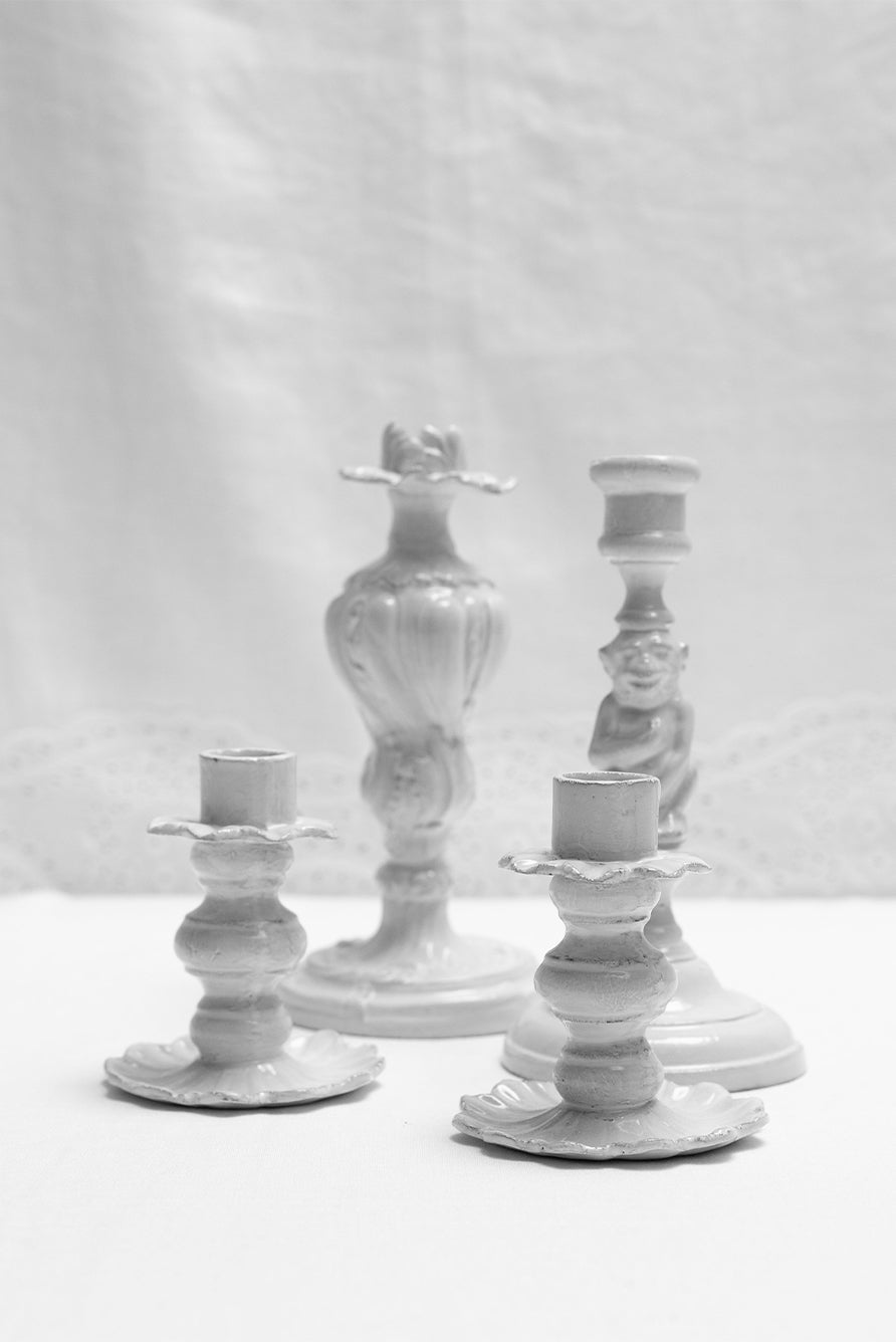 Set of white ceramic candle holders on a white broderie anglaise linen background