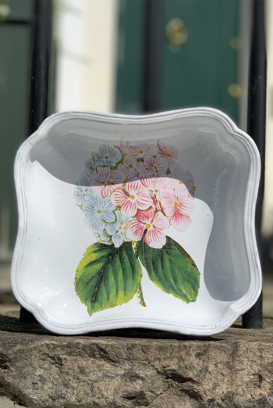 Decorative white deep plate with a pink and blue hydrangea flower design on a stone surface
