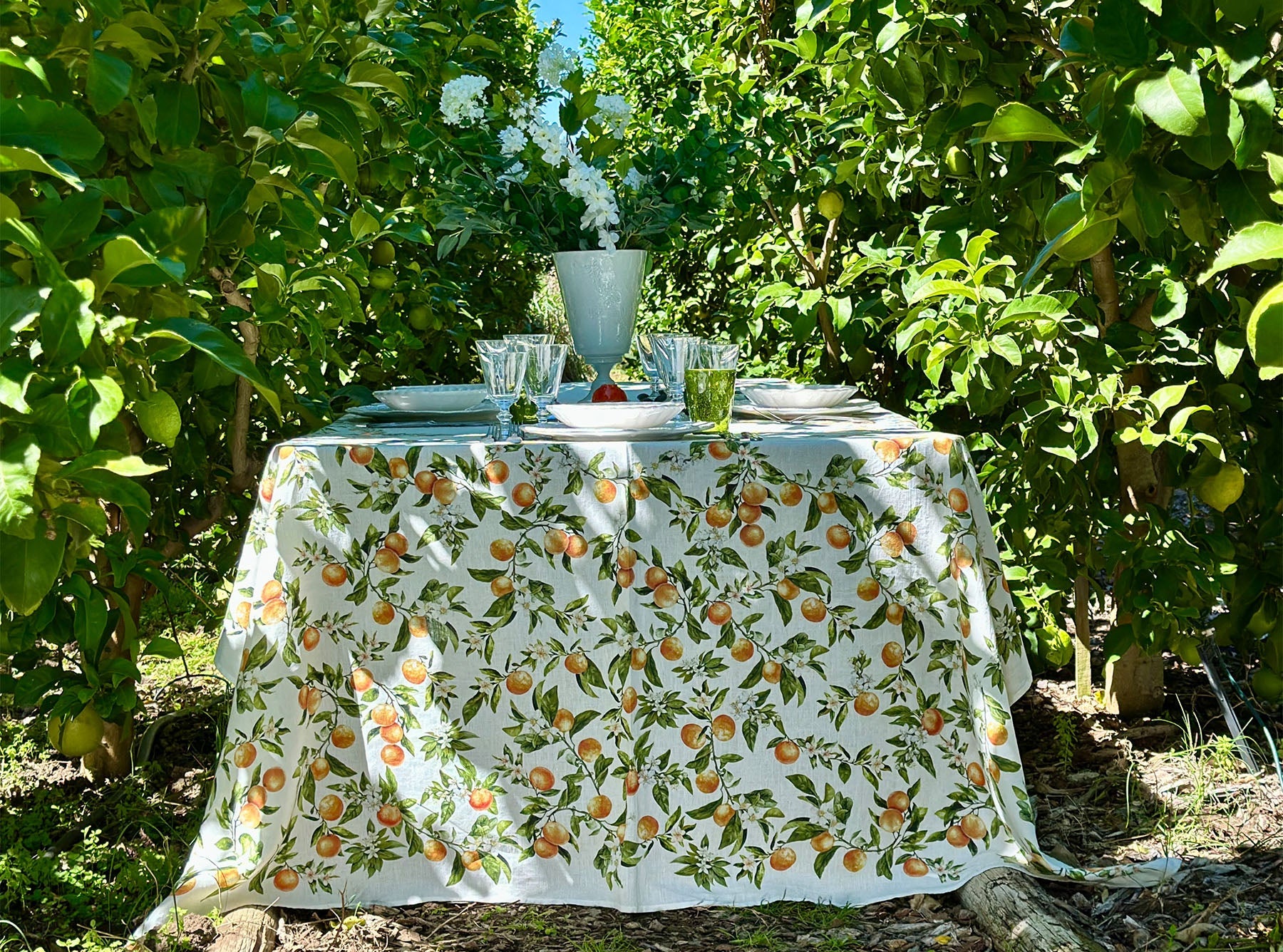 Table set with a orange themed linen tablecloth in an orchard