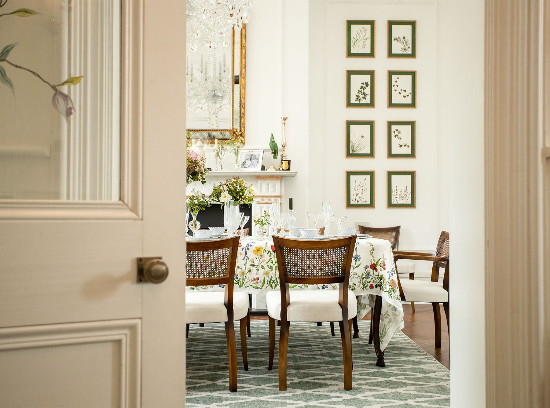 Dining room with a table dressed in Botanical Wildflower tablecloth set for a meal, chairs, and decorative elements.