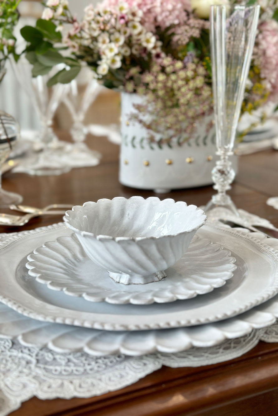 Elegant white ceramic Peggy set on a place placemat and wooden table with floral decorations.